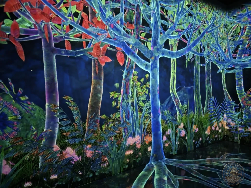Vivid immersive digital forest with glowing blue trees and colorful foliage at teamLab Forest Fukuoka, Japan. teamLab art installation. Fukuoka Cruise Port Guide | Things to do in Fukuoka from cruise ship | One day in Fukuoka Japan itinerary by Danny and Peter.