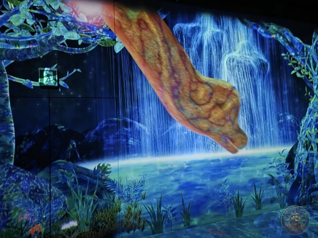 Immersive glowing dinosaur with dramatic waterfall in the digital forest at teamLab Forest Fukuoka, Japan. teamLab art experience. Fukuoka Cruise Port Guide | Things to do in Fukuoka from cruise ship | One day in Fukuoka Japan itinerary by Danny and Peter.