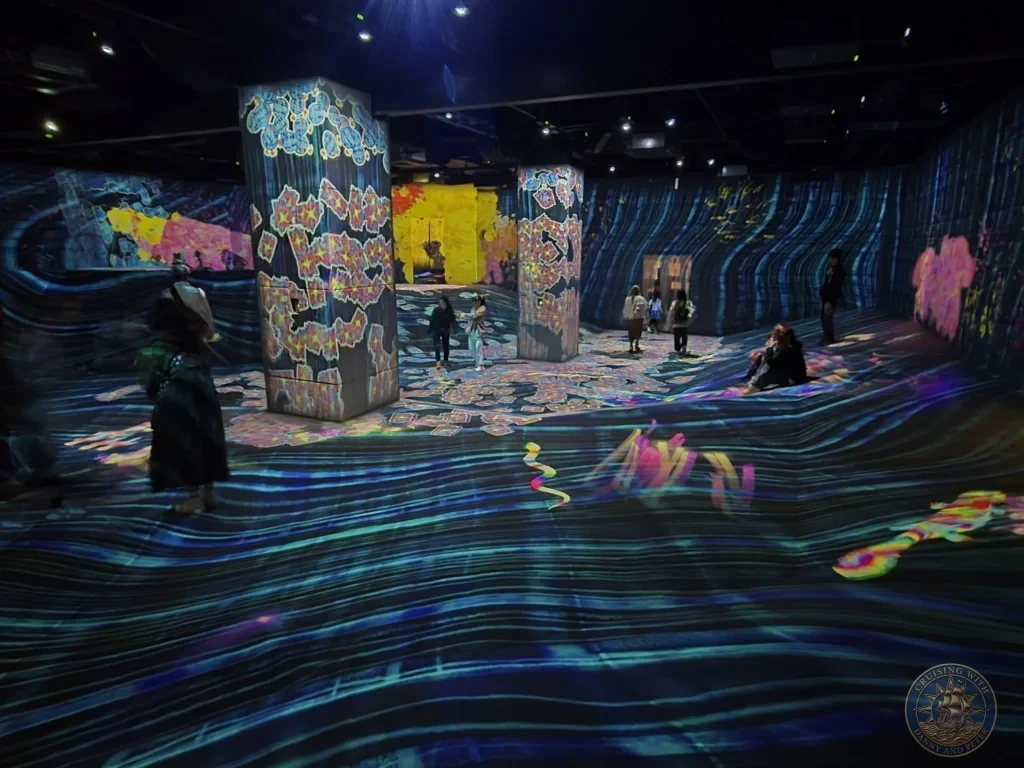 Expansive immersive digital art room with wavy glowing floor and colorful light towers at teamLab Forest Fukuoka, Japan. teamLab installation. Fukuoka Cruise Port Guide | Things to do in Fukuoka from cruise ship | One day in Fukuoka Japan itinerary by Danny and Peter.