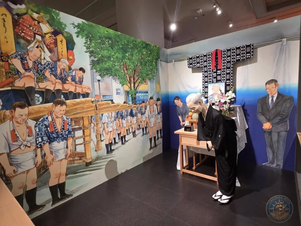 Memorial exhibit with bowing elder mannequin at altar and large mural at Fukuoka City Museum, Japan. Yamakasa cultural display. Fukuoka Cruise Port Guide | Things to do in Fukuoka from cruise ship | One day in Fukuoka Japan itinerary by Danny and Peter.