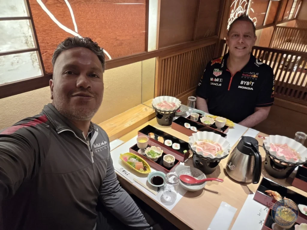 Kobe Japan Cruise Port Guide 2026 – Insider Tips & One Day Itinerary 28 Danny and Peter smiling for a selfie at a traditional Japanese restaurant table filled with sushi, shabu-shabu, and side dishes in Dotonbori, Osaka. Delicious dinner stop from Kobe port day. Kobe Japan Cruise Port Guide | DIY Kobe Cruise Port to City Center | Things to do in Kobe from cruise ship | Westerdam Kobe Docking Location | One day in Kobe Japan itinerary by Danny and Peter.