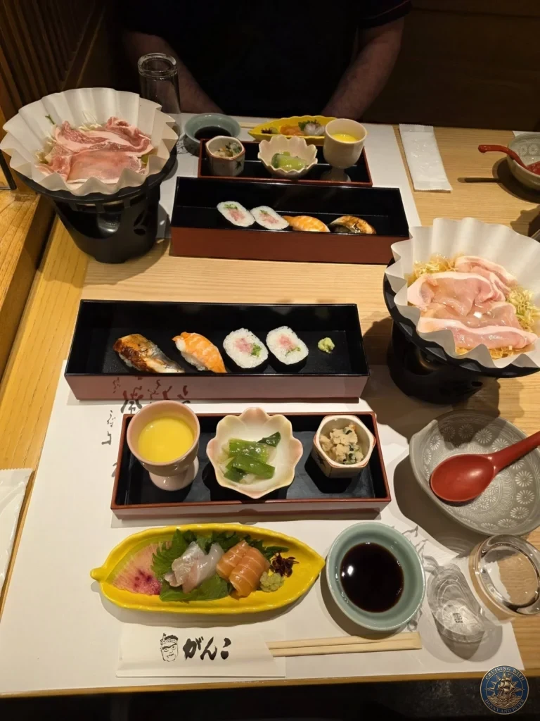 Kobe Japan Cruise Port Guide 2026 – Insider Tips & One Day Itinerary 29 Japanese dinner at Ganko in Dotonbori featuring sushi, sashimi, shabu-shabu meat, and side dishes on a wooden table in Osaka, Japan. Delicious meal from Kobe port day. Kobe Japan Cruise Port Guide | DIY Kobe Cruise Port to City Center | Things to do in Kobe from cruise ship | Westerdam Kobe Docking Location | One day in Kobe Japan itinerary by Danny and Peter.