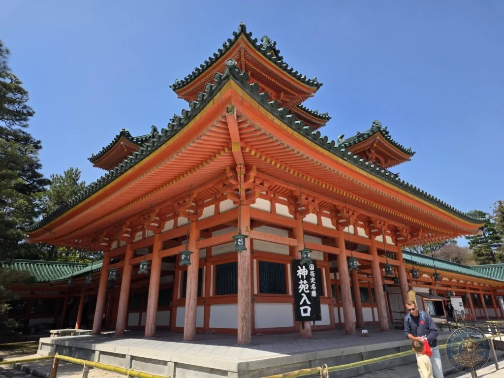 Kobe Japan Cruise Port Guide 2026 – Insider Tips & One Day Itinerary 2 Large red and green traditional Japanese hall marking the garden entrance at Heian Shrine under a clear blue sky in Kyoto, Japan. Shrine grounds from Kobe port day. Kobe Japan Cruise Port Guide | DIY Kobe Cruise Port to City Center | Things to do in Kobe from cruise ship | Westerdam Kobe Docking Location | One day in Kobe Japan itinerary by Danny and Peter.
