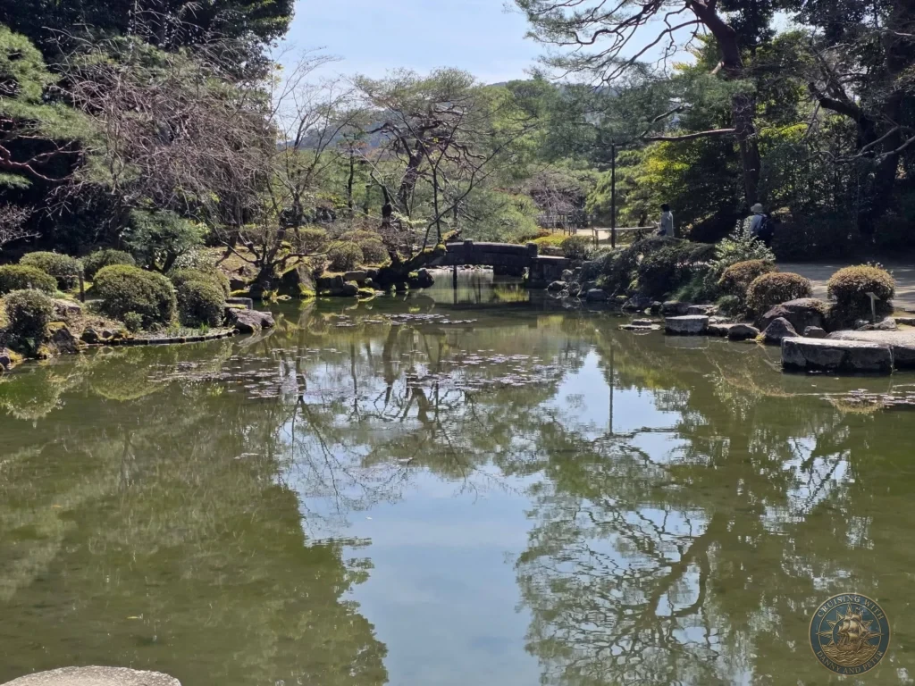 Kobe Japan Cruise Port Guide 2026 – Insider Tips & One Day Itinerary 55 Peaceful pond with tree reflections and a stone bridge in the gardens of Heian Shrine under a clear blue sky in Kyoto, Japan. Beautiful shrine gardens from Kobe port day. Kobe Japan Cruise Port Guide | DIY Kobe Cruise Port to City Center | Things to do in Kobe from cruise ship | Westerdam Kobe Docking Location | One day in Kobe Japan itinerary by Danny and Peter.