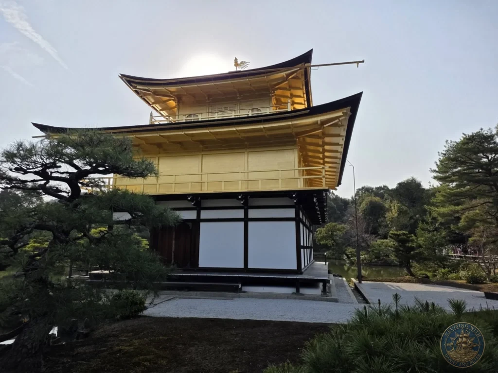 Kobe Japan Cruise Port Guide 2026 – Insider Tips & One Day Itinerary 69 Golden Pavilion (Kinkaku-ji) glowing with sunlight behind the roof, pine trees and pond in Kyoto, Japan. Temple view from Kobe port day. Kobe Japan Cruise Port Guide | DIY Kobe Cruise Port to City Center | Things to do in Kobe from cruise ship | Westerdam Kobe Docking Location | One day in Kobe Japan itinerary by Danny and Peter.