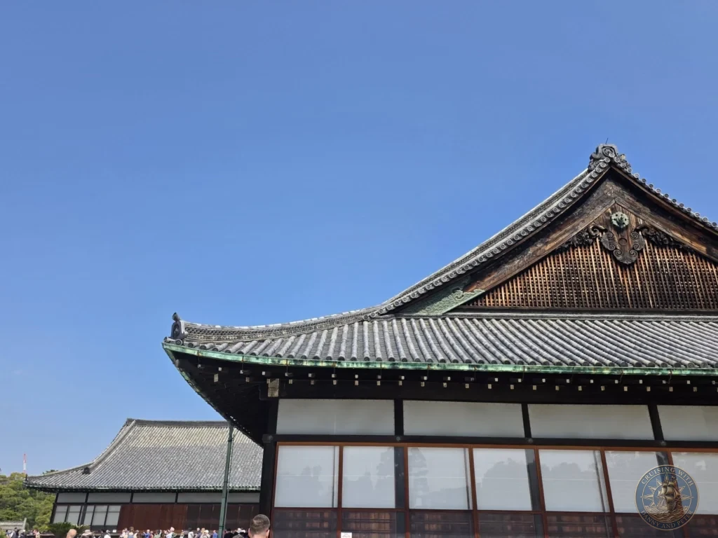 Kobe Japan Cruise Port Guide 2026 – Insider Tips & One Day Itinerary 71 Traditional tiled roofs and wooden architecture of Nijo Castle under a clear blue sky in Kyoto, Japan. Historic site from Kobe port day. Kobe Japan Cruise Port Guide | DIY Kobe Cruise Port to City Center | Things to do in Kobe from cruise ship | Westerdam Kobe Docking Location | One day in Kobe Japan itinerary by Danny and Peter.