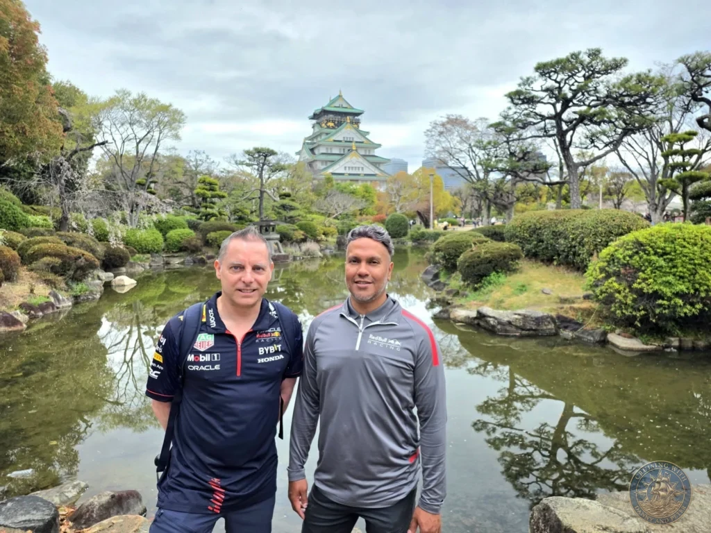 Kobe Japan Cruise Port Guide 2026 – Insider Tips & One Day Itinerary 103 Danny and Peter standing by a pond in the Osaka Castle gardens with the iconic castle keep rising in the background in Osaka, Japan. Historic garden view from Kobe port day. Kobe Japan Cruise Port Guide | DIY Kobe Cruise Port to City Center | Things to do in Kobe from cruise ship | Westerdam Kobe Docking Location | One day in Kobe Japan itinerary by Danny and Peter.