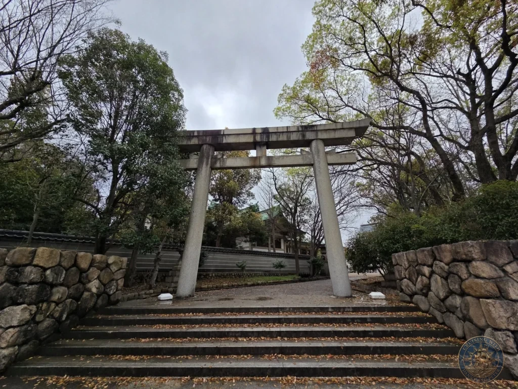 Kobe Japan Cruise Port Guide 2026 – Insider Tips & One Day Itinerary 122 Large stone torii gate standing at the top of stone steps surrounded by trees and walls at Osaka Castle in Osaka, Japan. Traditional entrance from Kobe port day. Kobe Japan Cruise Port Guide | DIY Kobe Cruise Port to City Center | Things to do in Kobe from cruise ship | Westerdam Kobe Docking Location | One day in Kobe Japan itinerary by Danny and Peter.