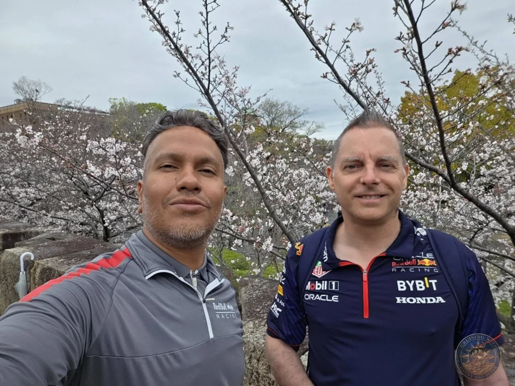 Kobe Japan Cruise Port Guide 2026 – Insider Tips & One Day Itinerary 124 Danny and Peter taking a selfie standing near stone walls surrounded by blooming cherry blossom trees at Osaka Castle Park on a spring day; ideal for a Kobe Japan Cruise Port Guide, DIY Kobe Cruise Port to City Center, Things to do in Kobe from cruise ship, Westerdam Kobe Docking Location, or One day in Kobe Japan itinerary, by Danny and Peter.