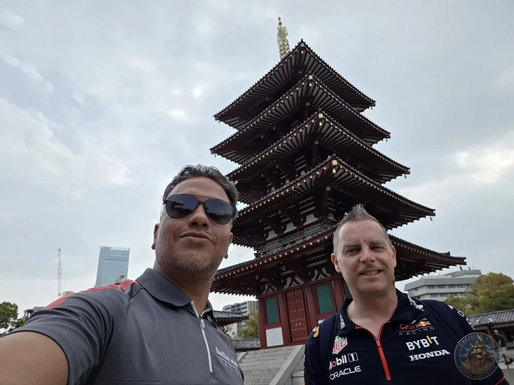 Kobe Japan Cruise Port Guide 2026 – Insider Tips & One Day Itinerary 134 Danny and Peter in Red Bull Racing shirts posing for a selfie in front of the five-story pagoda at Shitennoji Temple in Osaka under an overcast sky; ideal for a Kobe Japan Cruise Port Guide, DIY Kobe Cruise Port to City Center, Things to do in Kobe from cruise ship, MS Westerdam Kobe Docking Location, or One day in Kobe Japan itinerary, by Danny and Peter.