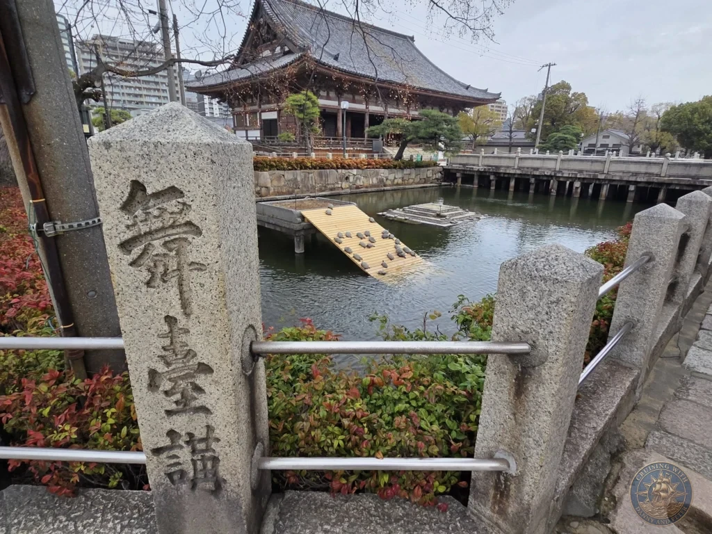 Kobe Japan Cruise Port Guide 2026 – Insider Tips & One Day Itinerary 137 A carved stone pillar in the foreground overlooking Kame-no-ike (Turtle Pond) with dozens of turtles sunbathing on wooden ramps at Shitennoji Temple in Osaka, Japan; ideal for a Kobe Japan Cruise Port Guide, DIY Kobe Cruise Port to City Center, Things to do in Kobe from cruise ship, MS Westerdam Kobe Docking Location, or One day in Kobe Japan itinerary, by Danny and Peter.
