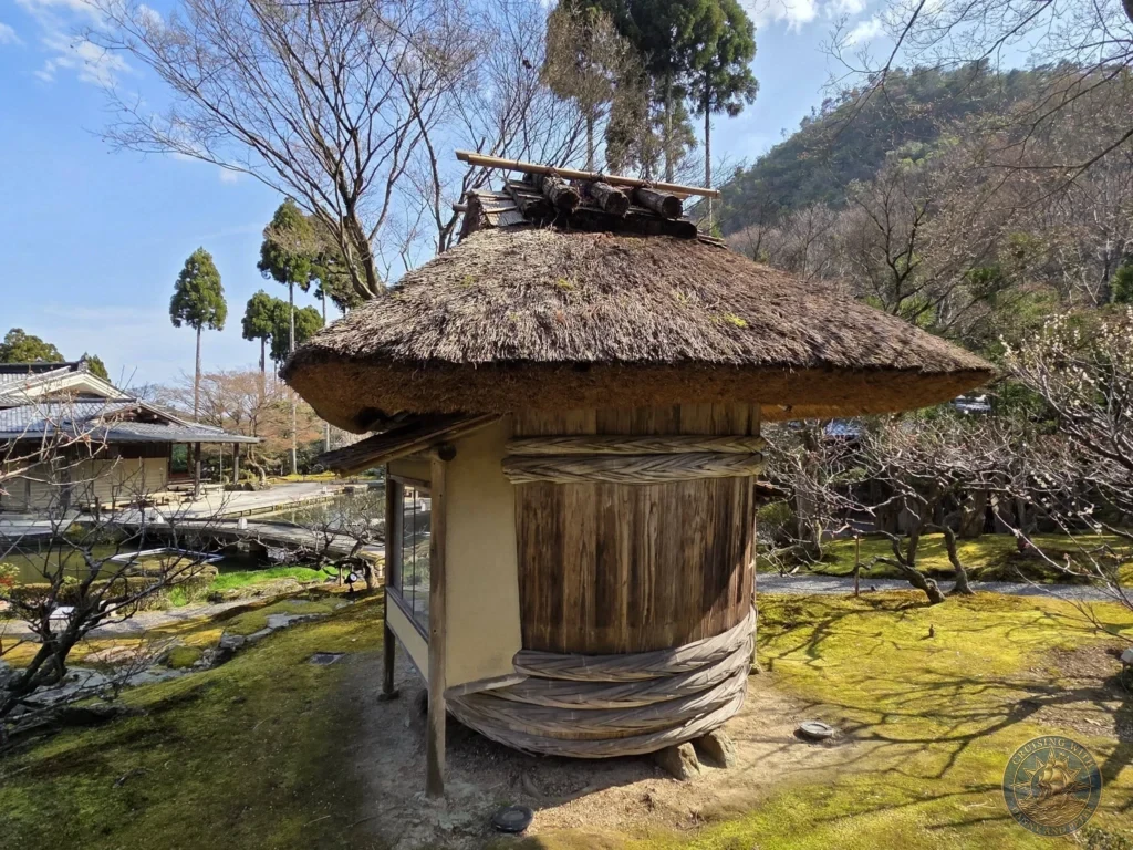 Kobe Japan Cruise Port Guide 2026 – Insider Tips & One Day Itinerary 83 Traditional thatched-roof pavilion standing in a mossy garden with a pond and trees at Shozan Resort under a blue sky in Kyoto, Japan. Peaceful garden architecture from Kobe port day. Kobe Japan Cruise Port Guide | DIY Kobe Cruise Port to City Center | Things to do in Kobe from cruise ship | Westerdam Kobe Docking Location | One day in Kobe Japan itinerary by Danny and Peter.