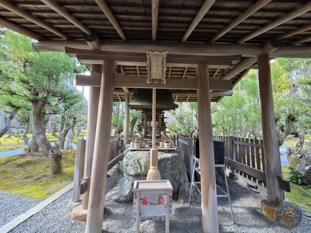 Kobe Japan Cruise Port Guide 2026 – Insider Tips & One Day Itinerary 87 Traditional wooden shrine pavilion with hanging rope, large rock, and offering box surrounded by pine trees and moss at Shozan Resort Garden in Kyoto, Japan. Quiet shrine corner from Kobe port day. Kobe Japan Cruise Port Guide | DIY Kobe Cruise Port to City Center | Things to do in Kobe from cruise ship | Westerdam Kobe Docking Location | One day in Kobe Japan itinerary by Danny and Peter.