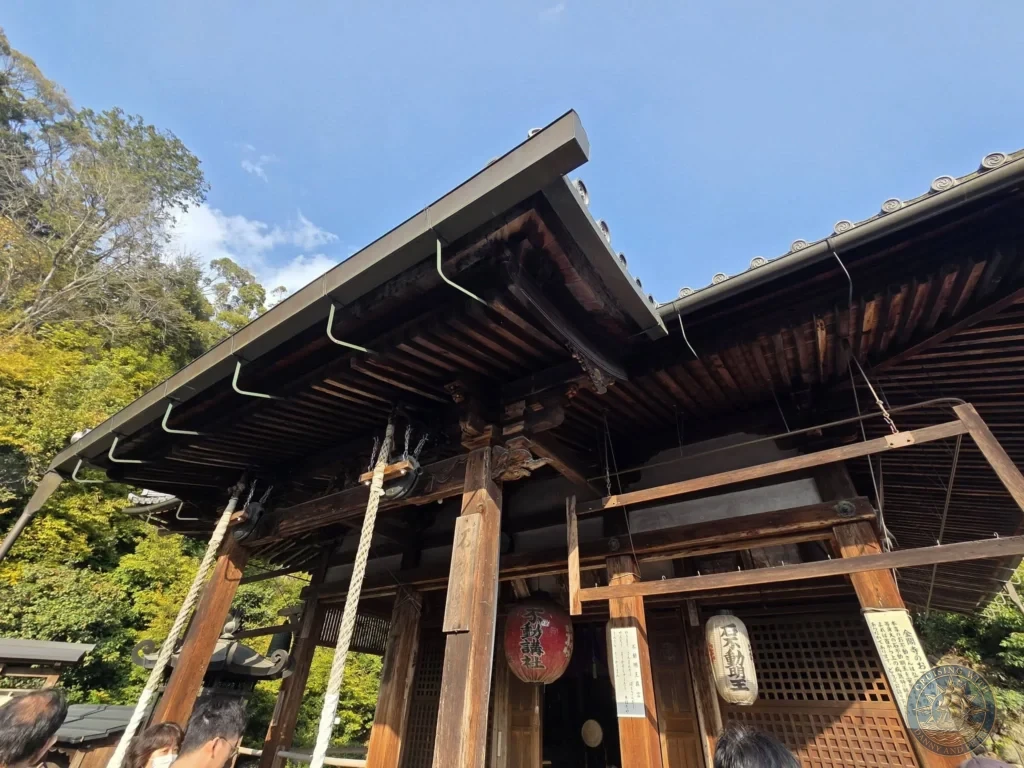 Kobe Japan Cruise Port Guide 2026 – Insider Tips & One Day Itinerary 90 Traditional wooden shrine entrance with hanging ropes, red lantern, and Japanese signs under a blue sky at Shozan Resort Garden in Kyoto, Japan. Quiet shrine detail from Kobe port day. Kobe Japan Cruise Port Guide | DIY Kobe Cruise Port to City Center | Things to do in Kobe from cruise ship | Westerdam Kobe Docking Location | One day in Kobe Japan itinerary by Danny and Peter.
