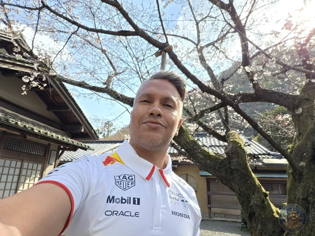 Kobe Japan Cruise Port Guide 2026 – Insider Tips & One Day Itinerary 93 Danny taking a selfie under a blooming cherry blossom tree with traditional buildings in the background at Shozan Resort Garden in Kyoto, Japan. Spring garden stop from Kobe port day. Kobe Japan Cruise Port Guide | DIY Kobe Cruise Port to City Center | Things to do in Kobe from cruise ship | Westerdam Kobe Docking Location | One day in Kobe Japan itinerary by Danny and Peter.