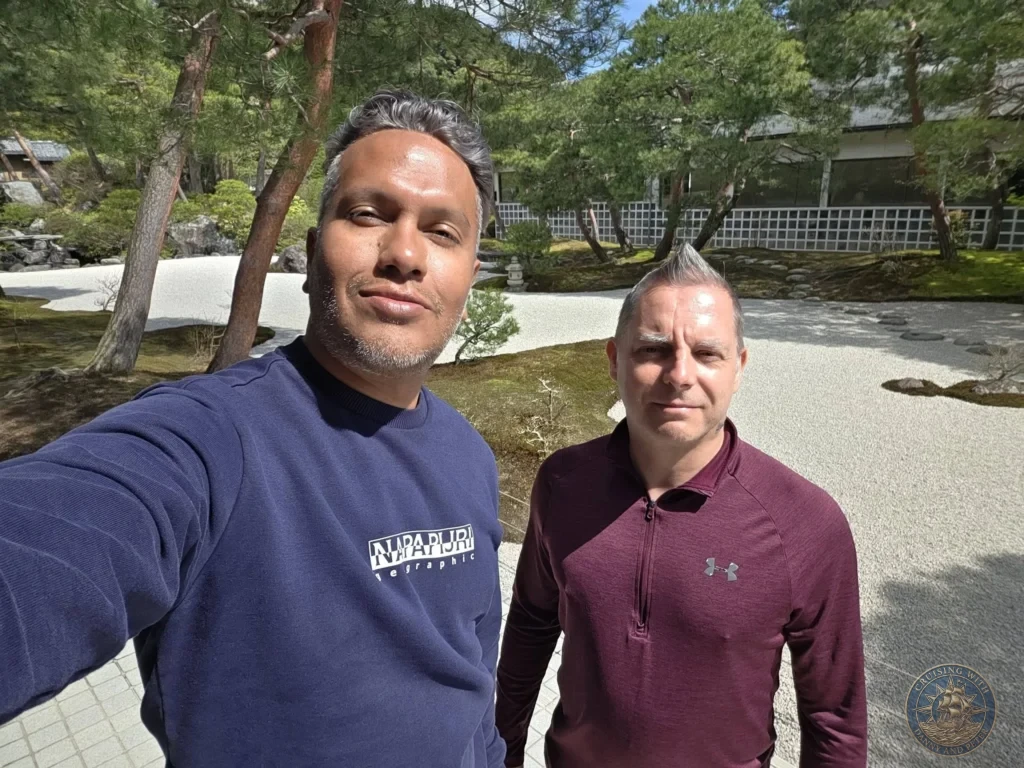 Selfie taken outdoors in front of the raked white gravel and pine trees of the Japanese garden at the Adachi Museum of Art during a shore excursion from Sakaiminato Japan Cruise Port Guide, DIY Sakaiminato Cruise Port to City Center, Things to do in Sakaiminato from cruise ship, Westerdam Sakaiminato Docking Location, One day in Sakaiminato Japan itinerary by Danny and Peter.