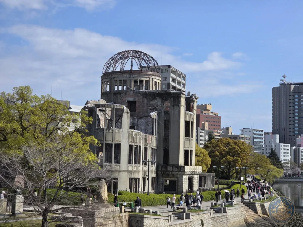 Hiroshima Japan Cruise Port Guide 2026 – Insider Tips & One Day Itinerary 4 The preserved skeletal iron frame and gutted walls of the Atomic Bomb Dome along the Motoyasu Riverbank during a sunny day in Hiroshima Japan. Hiroshima Japan Cruise Port Guide, DIY Hiroshima Cruise Port to City Center, Things to do in Hiroshima from cruise ship, Westerdam Hiroshima Docking Location, One day in Hiroshima Japan itinerary by Danny and Peter.