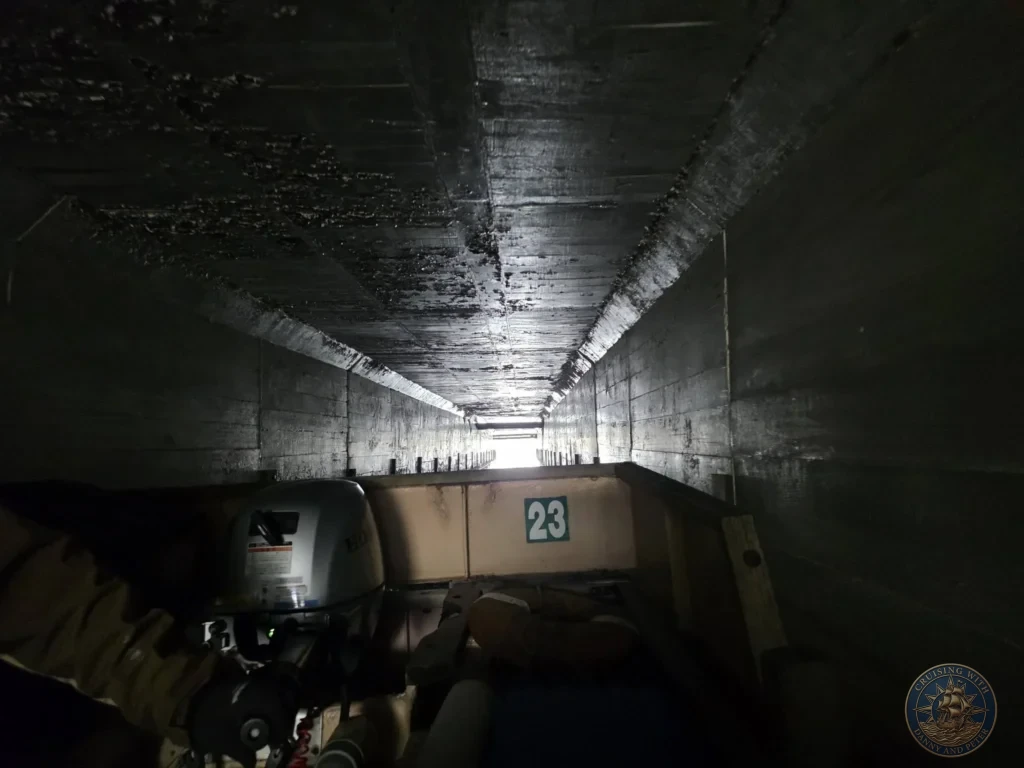 View looking forward through a dark low-clearance bridge tunnel on the Horikawa Sightseeing Boat with light visible at the end during a shore excursion from Sakaiminato Japan Cruise Port Guide, DIY Sakaiminato Cruise Port to City Center, Things to do in Sakaiminato from cruise ship, Westerdam Sakaiminato Docking Location, One day in Sakaiminato Japan itinerary by Danny and Peter.