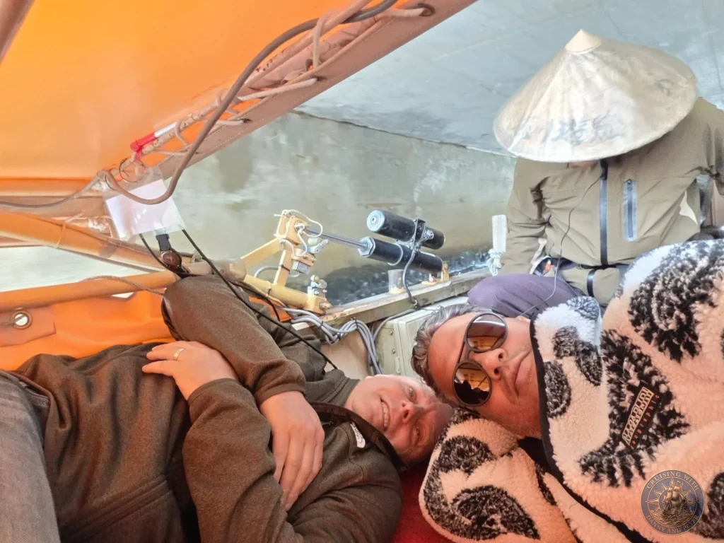 Danny and Peter lying completely flat inside the Horikawa Sightseeing Boat as the canopy lowers under a low bridge with the boat captain steering in the background in Matsue during a shore excursion from Sakaiminato Japan Cruise Port Guide, DIY Sakaiminato Cruise Port to City Center, Things to do in Sakaiminato from cruise ship, Westerdam Sakaiminato Docking Location, One day in Sakaiminato Japan itinerary by Danny and Peter.