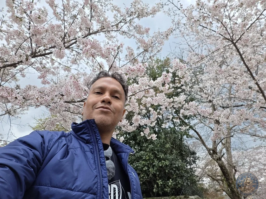 Hiroshima Japan Cruise Port Guide 2026 – Insider Tips & One Day Itinerary 39 Selfie framed by full blooming cherry blossom tree branches overhead on Miyajima Island in Hiroshima Japan. Hiroshima Japan Cruise Port Guide, DIY Hiroshima Cruise Port to City Center, Things to do in Hiroshima from cruise ship, Westerdam Hiroshima Docking Location, One day in Hiroshima Japan itinerary by Danny and Peter.