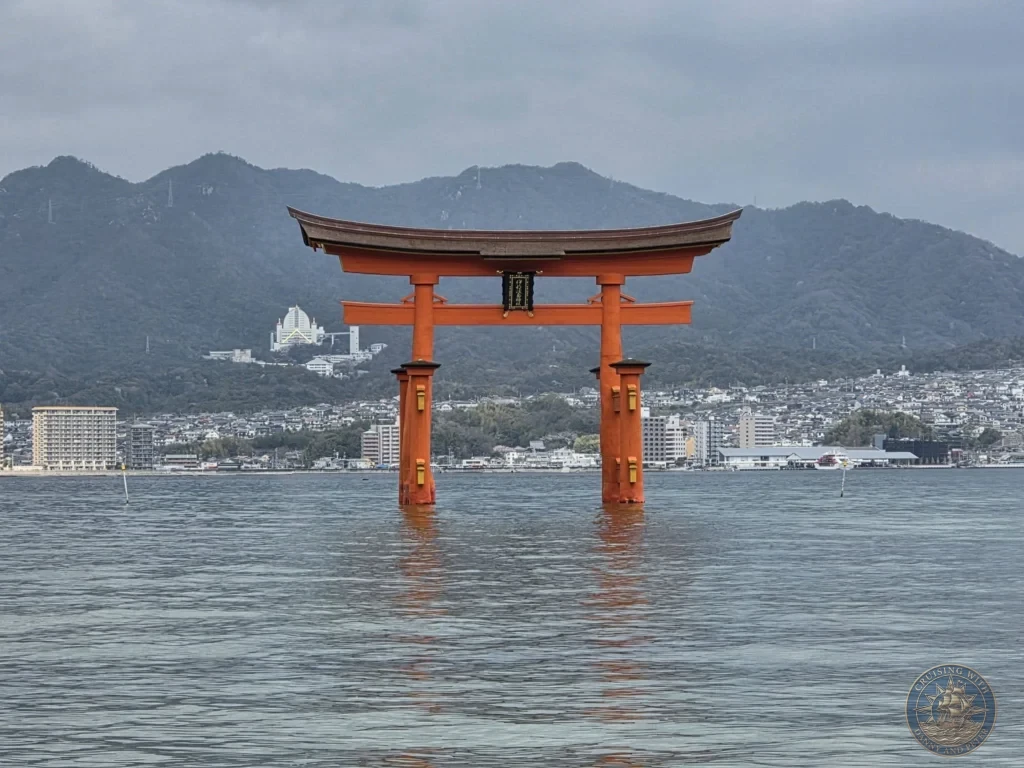 Hiroshima Japan Cruise Port Guide 2026 – Insider Tips & One Day Itinerary 26 Direct frontal shot of the iconic red Grand Torii Gate of Itsukushima Shrine standing in calm sea waters at high tide against the backdrop of mainland mountains in Hiroshima Japan. Hiroshima Japan Cruise Port Guide, DIY Hiroshima Cruise Port to City Center, Things to do in Hiroshima from cruise ship, Westerdam Hiroshima Docking Location, One day in Hiroshima Japan itinerary by Danny and Peter.