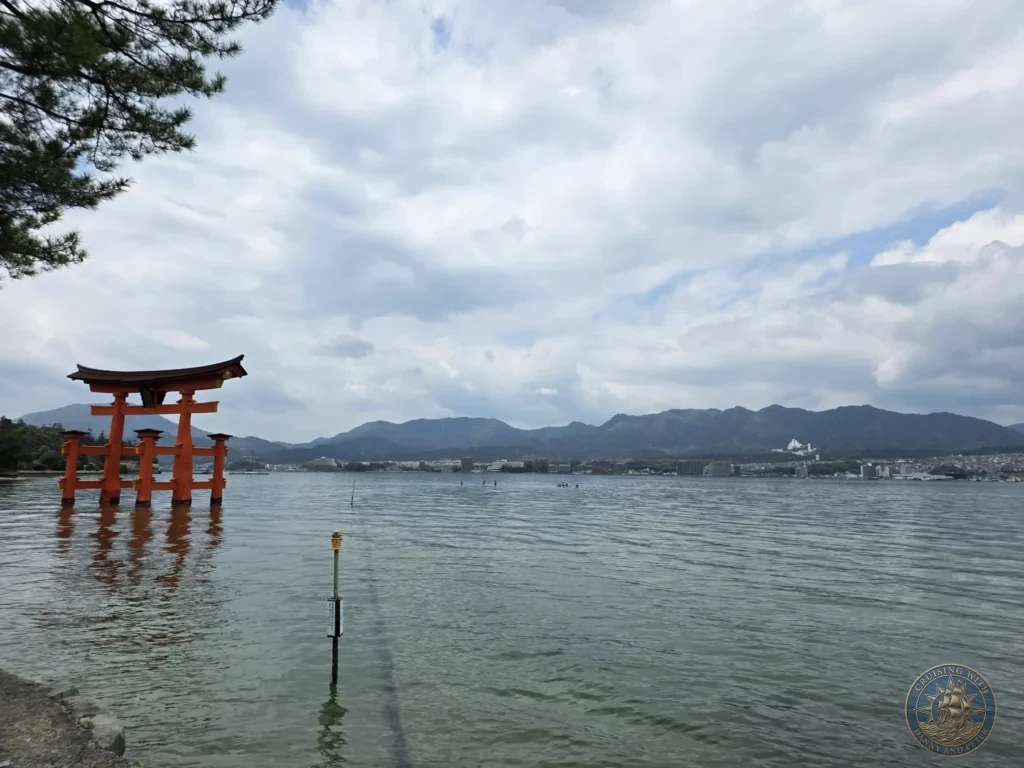 Hiroshima Japan Cruise Port Guide 2026 – Insider Tips & One Day Itinerary 34 Wide landscape view of the Grand Torii Gate standing in the water off Miyajima Island with distant mountains across the bay in Hiroshima Japan. Hiroshima Japan Cruise Port Guide, DIY Hiroshima Cruise Port to City Center, Things to do in Hiroshima from cruise ship, Westerdam Hiroshima Docking Location, One day in Hiroshima Japan itinerary by Danny and Peter.