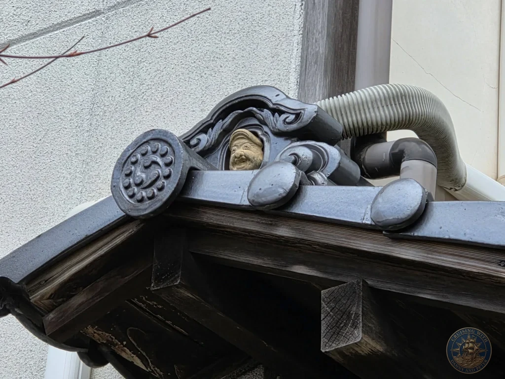 Close-up of an ornate traditional Japanese black roof tile featuring a carved face ornament on the eaves of Kyoragi restaurant in Matsue during a shore excursion from Sakaiminato Japan Cruise Port Guide, DIY Sakaiminato Cruise Port to City Center, Things to do in Sakaiminato from cruise ship, Westerdam Sakaiminato Docking Location, One day in Sakaiminato Japan itinerary by Danny and Peter.