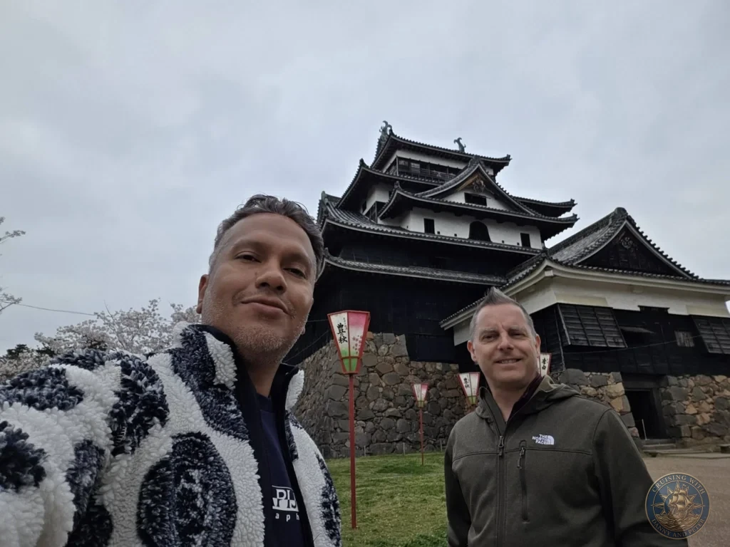 Danny and Peter taking a selfie together directly in front of the historic wooden keep of Matsue Castle during a shore excursion from Sakaiminato Japan Cruise Port Guide, DIY Sakaiminato Cruise Port to City Center, Things to do in Sakaiminato from cruise ship, Westerdam Sakaiminato Docking Location, One day in Sakaiminato Japan itinerary by Danny and Peter.