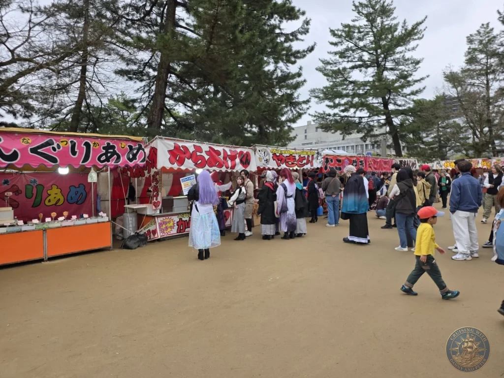 Busy festival food stalls selling Japanese street food like karaage and yakitori surrounded by visitors at Matsue Castle grounds during a shore excursion from Sakaiminato Japan Cruise Port Guide, DIY Sakaiminato Cruise Port to City Center, Things to do in Sakaiminato from cruise ship, Westerdam Sakaiminato Docking Location, One day in Sakaiminato Japan itinerary by Danny and Peter.