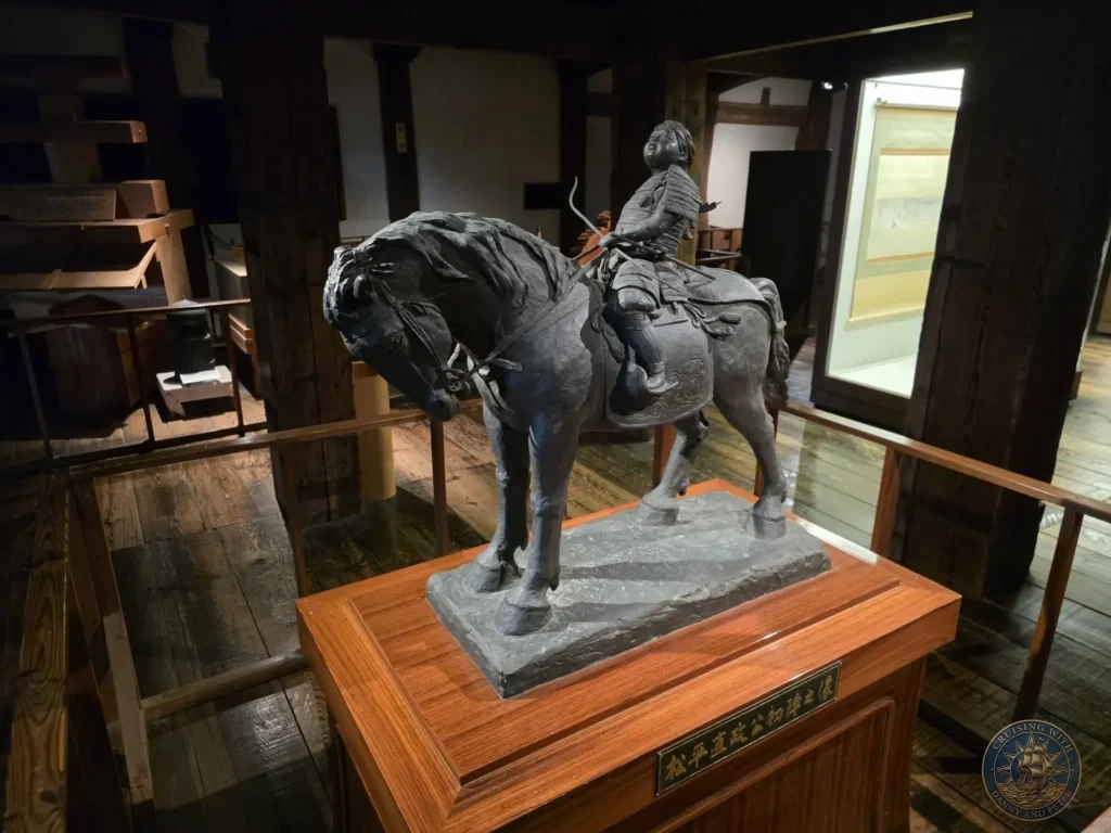 Detailed bronze statue of young Matsudaira Naomasa in samurai armor riding a horse displayed on a wooden pedestal inside Matsue Castle keep during a shore excursion from Sakaiminato Japan Cruise Port Guide, DIY Sakaiminato Cruise Port to City Center, Things to do in Sakaiminato from cruise ship, Westerdam Sakaiminato Docking Location, One day in Sakaiminato Japan itinerary by Danny and Peter.