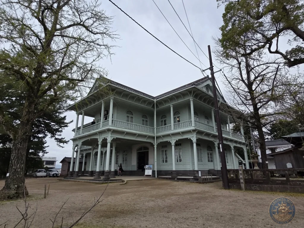 Two-story pale green Western-style wooden building with wrap-around verandas and decorative pillars situated on the grounds of Matsue Castle during a shore excursion from Sakaiminato Japan Cruise Port Guide, DIY Sakaiminato Cruise Port to City Center, Things to do in Sakaiminato from cruise ship, Westerdam Sakaiminato Docking Location, One day in Sakaiminato Japan itinerary by Danny and Peter.