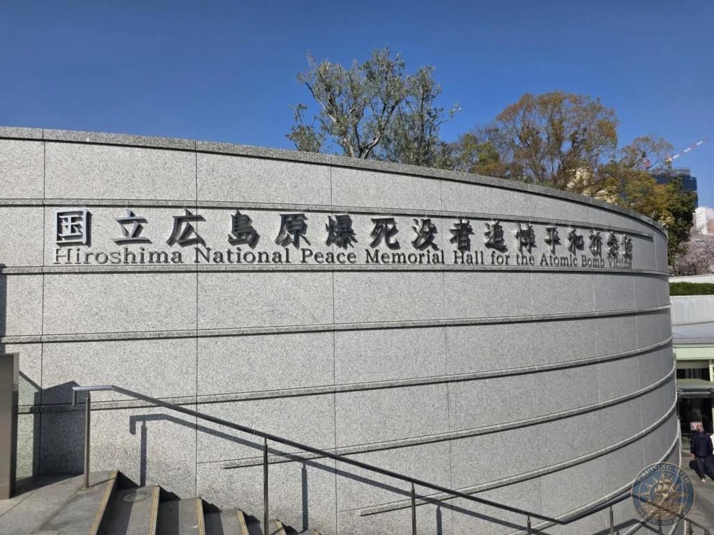 Hiroshima Japan Cruise Port Guide 2026 – Insider Tips & One Day Itinerary 62 The curved stone exterior and entrance staircase of the Hiroshima National Peace Memorial Hall for the Atomic Bomb Victims under a clear blue sky in Hiroshima Japan. Hiroshima Japan Cruise Port Guide, DIY Hiroshima Cruise Port to City Center, Things to do in Hiroshima from cruise ship, Westerdam Hiroshima Docking Location, One day in Hiroshima Japan itinerary by Danny and Peter.