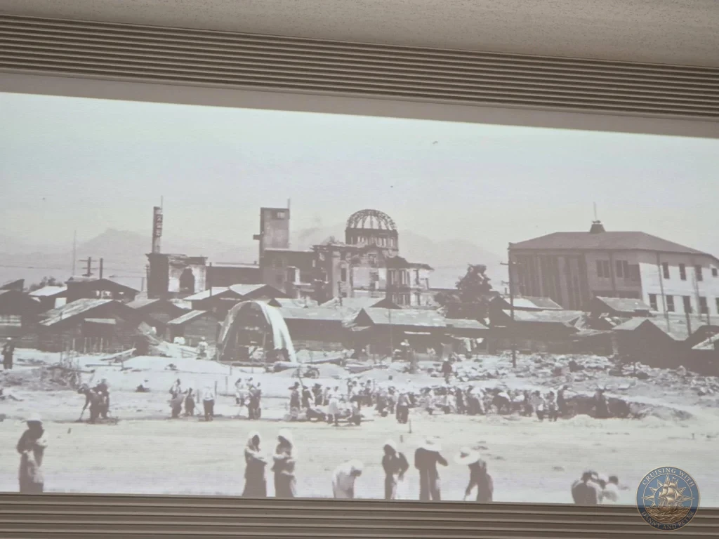 Hiroshima Japan Cruise Port Guide 2026 – Insider Tips & One Day Itinerary 63 Historical monochrome panoramic photo exhibition inside the Hiroshima National Peace Memorial Hall showing people walking near destroyed buildings and the Atomic Bomb Dome in Hiroshima Japan. Hiroshima Japan Cruise Port Guide, DIY Hiroshima Cruise Port to City Center, Things to do in Hiroshima from cruise ship, Westerdam Hiroshima Docking Location, One day in Hiroshima Japan itinerary by Danny and Peter.