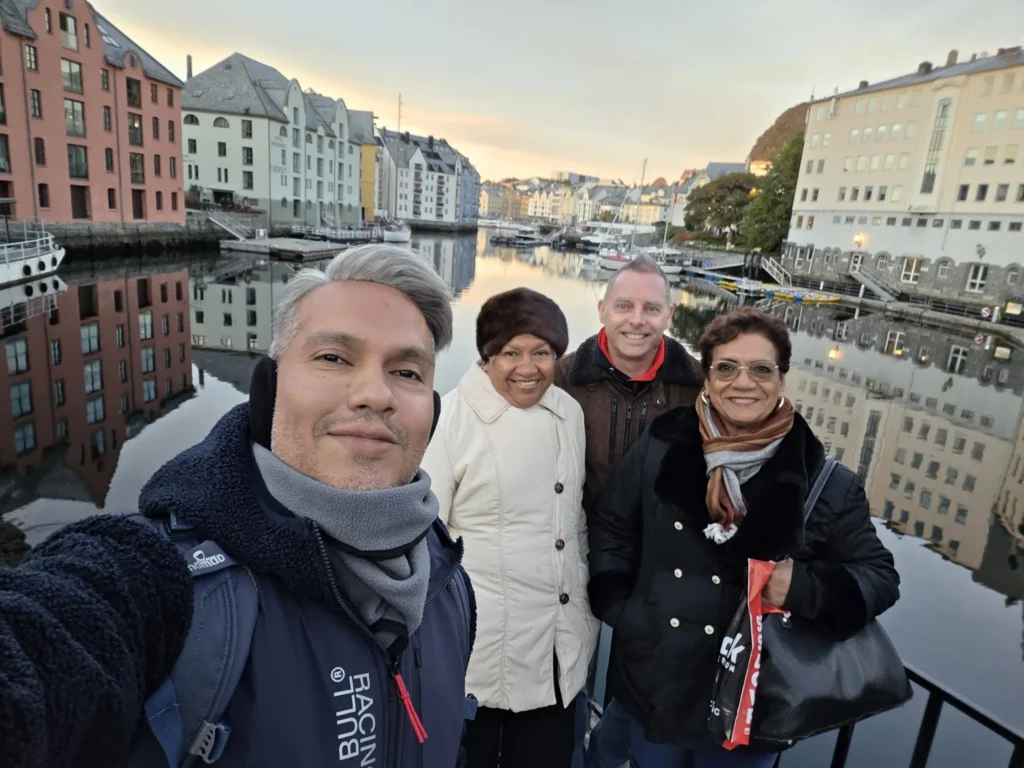 Danny taking a group selfie with Peter and family along the scenic Brosundet Canal lined with Art Nouveau buildings during a Holland America Rotterdam shore excursion stop. Things to do in Ålesund from cruise ship, by Danny and Peter.