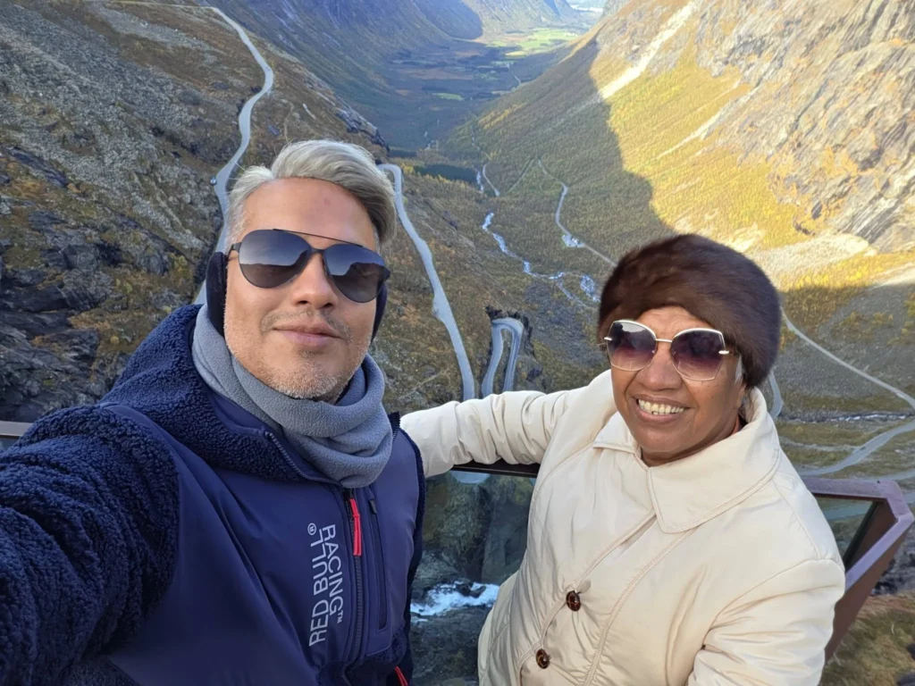 Danny taking a selfie with his mother at the Trollstigen viewpoint, high above the winding hairpin bends and valley near Ålesund, Norway. Things to do in Ålesund from cruise ship, by Danny and Peter.