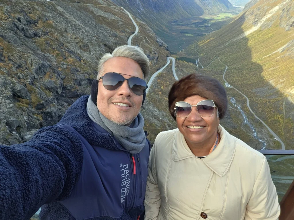 Danny taking a selfie with his mother on the Trollstigen observation deck overlooking the valley and winding road near Ålesund, Norway. Things to do in Ålesund from cruise ship, by Danny and Peter.