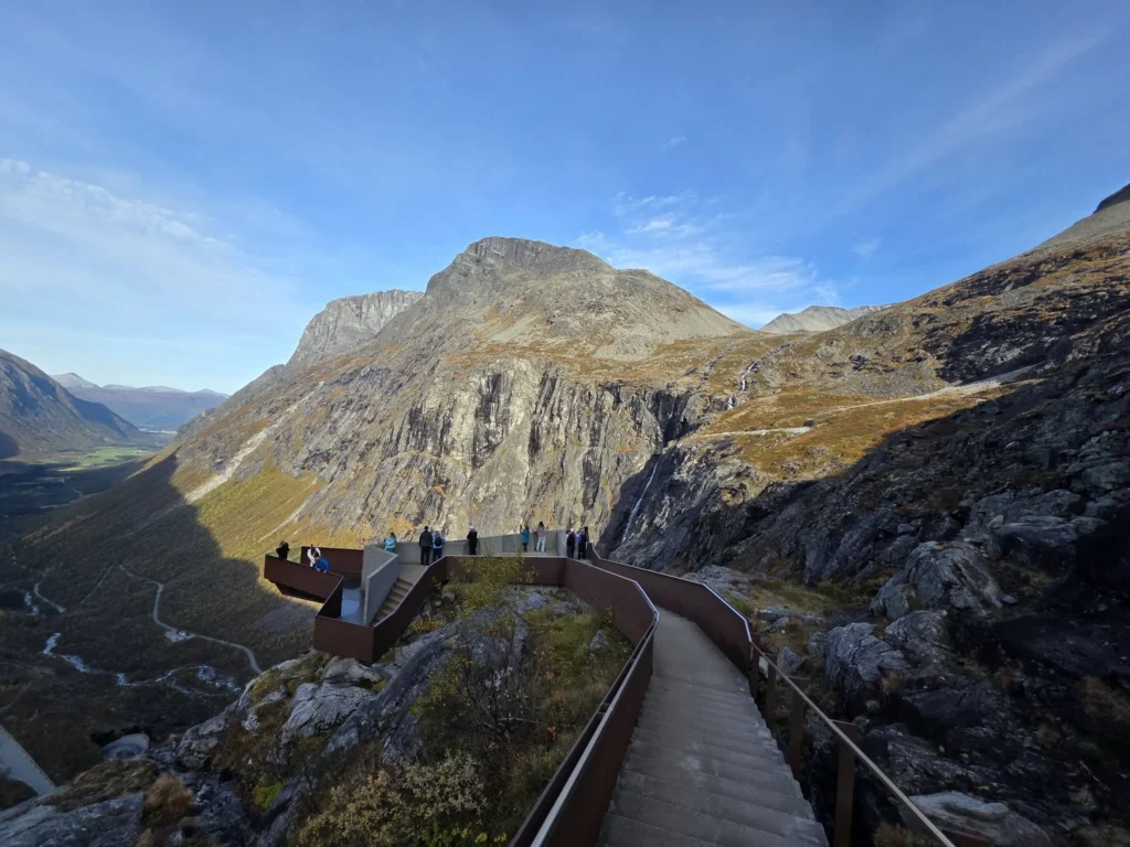 A modern concrete and steel cantilevered walkway leads visitors to the Trollstigen viewing platform suspended over steep mountain cliffs near Ålesund, Norway. Things to do in Ålesund from cruise ship, by Danny and Peter.