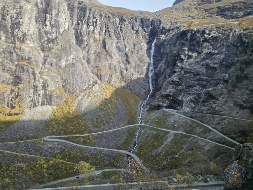 A narrow waterfall cascading down dramatic steep rocky mountain walls alongside the winding hairpin road of Trollstigen near Ålesund, Norway. Things to do in Ålesund from cruise ship, by Danny and Peter.